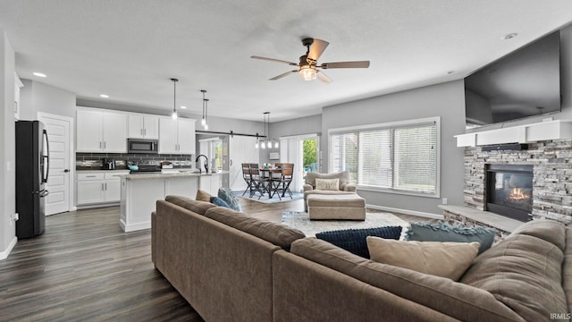 living room featuring ceiling fan, recessed lighting, a fireplace, baseboards, and dark wood-style floors