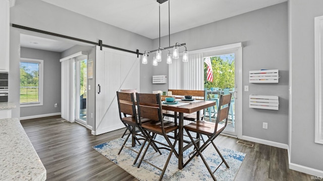 dining room with a barn door, dark wood-type flooring, visible vents, and baseboards