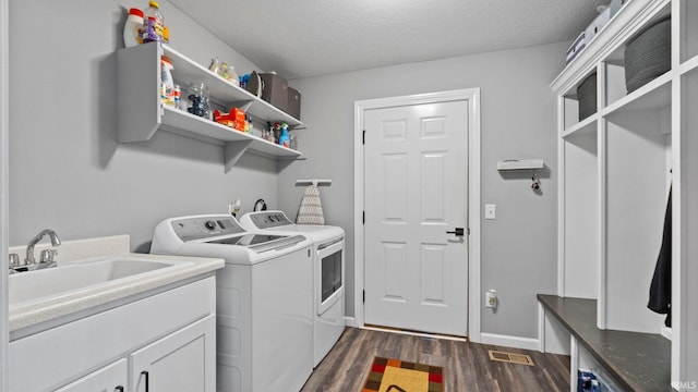 laundry room with a textured ceiling, dark wood-style flooring, a sink, visible vents, and washer and clothes dryer