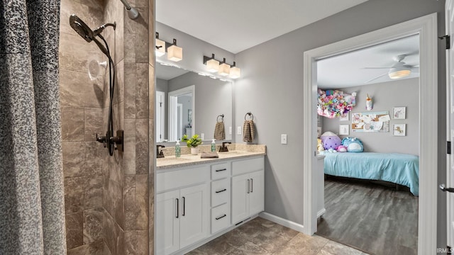 ensuite bathroom featuring double vanity, baseboards, ensuite bathroom, a tile shower, and a sink