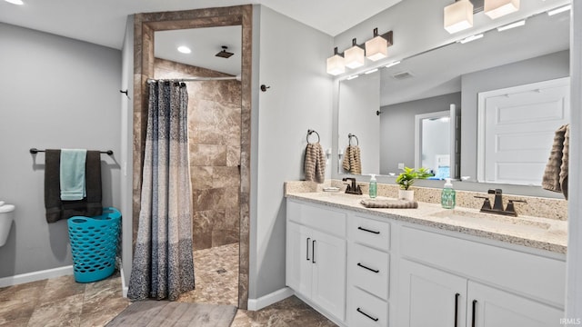 full bathroom featuring a sink, a tile shower, baseboards, and double vanity