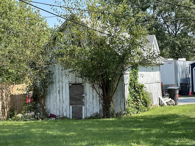 view of side of home with a yard, a detached garage, and fence