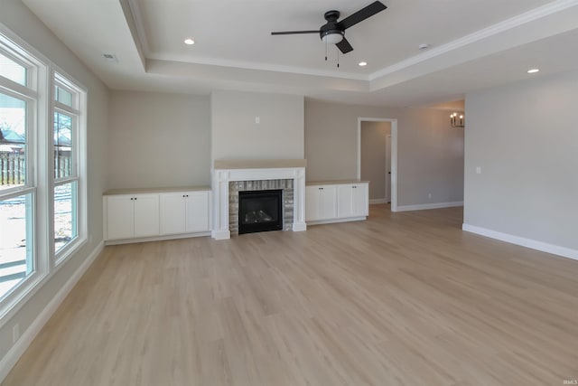 unfurnished living room with crown molding, ceiling fan with notable chandelier, light hardwood / wood-style flooring, and a raised ceiling