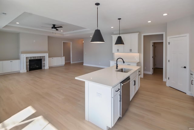 kitchen featuring dishwasher, white cabinetry, sink, a kitchen island with sink, and a raised ceiling