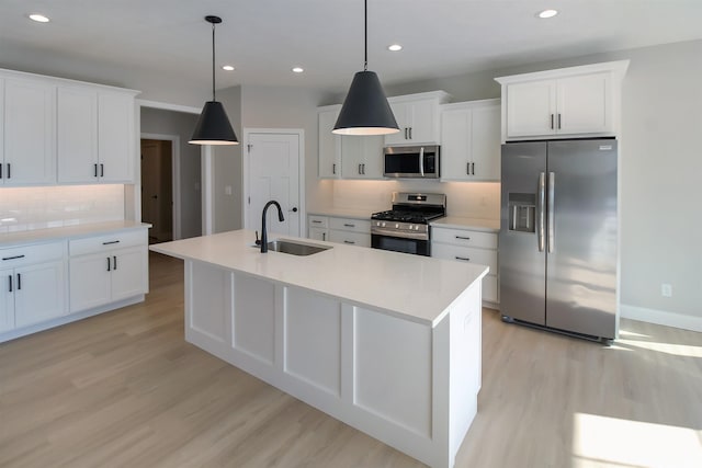 kitchen featuring sink, decorative light fixtures, stainless steel appliances, and a center island with sink