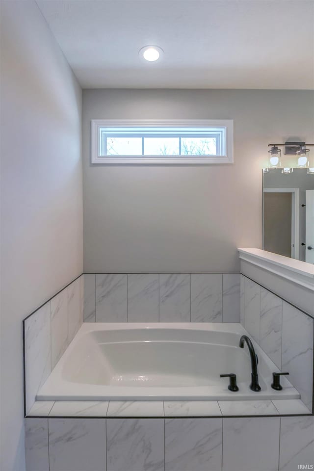 bathroom featuring a healthy amount of sunlight and tiled tub