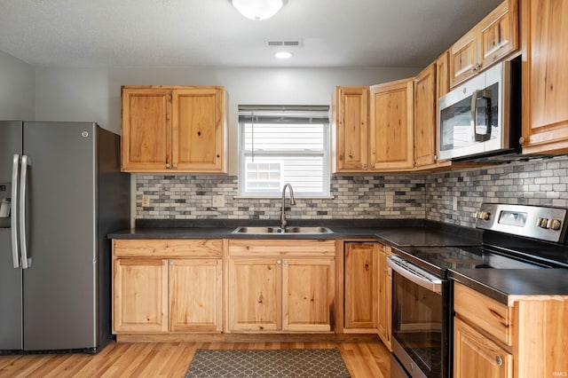 3128 Springwater Ct, Kokomo, IN 46902 - kitchen featuring stainless steel appliances, a sink, dark countertops, light wood-style flooring, and backsplash