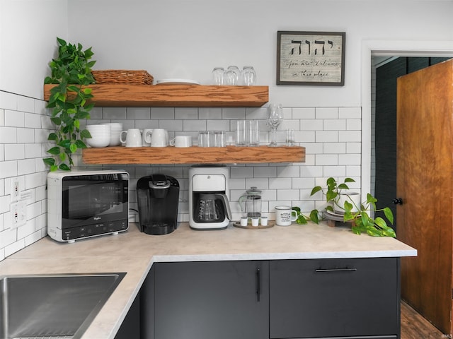 kitchen featuring open shelves, backsplash, a sink, and light countertops