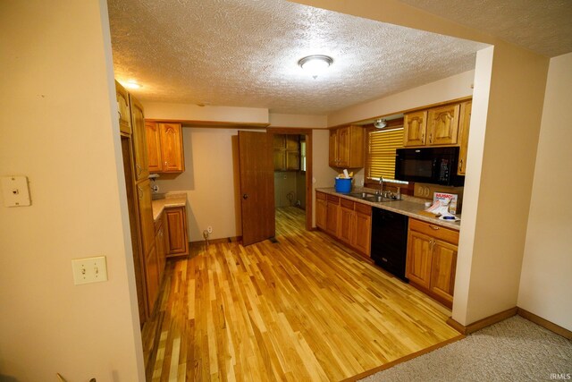 kitchen with sink, light hardwood / wood-style flooring, a textured ceiling, and black appliances