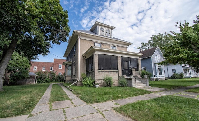 american foursquare style home with a front yard, a sunroom, and brick siding