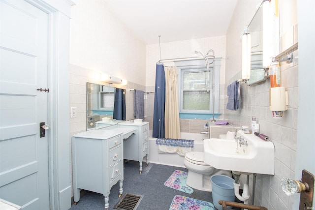 bathroom with visible vents, toilet, tile walls, and shower / tub combo with curtain