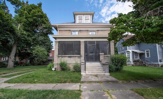 view of front of property featuring a sunroom and a front lawn