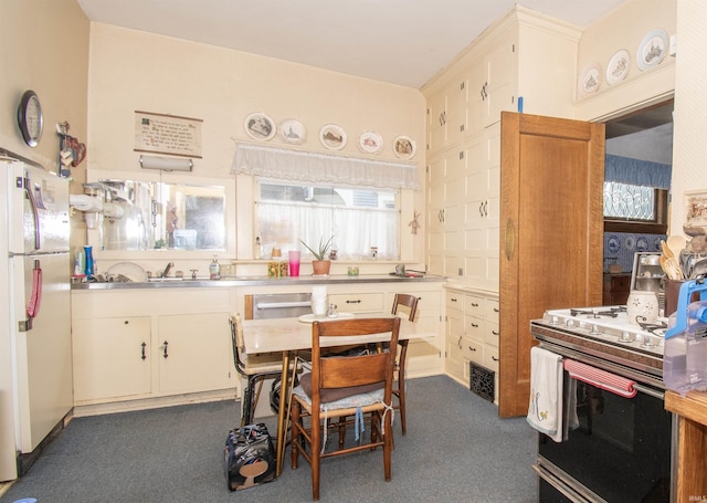 kitchen with freestanding refrigerator, pendant lighting, light countertops, and stove