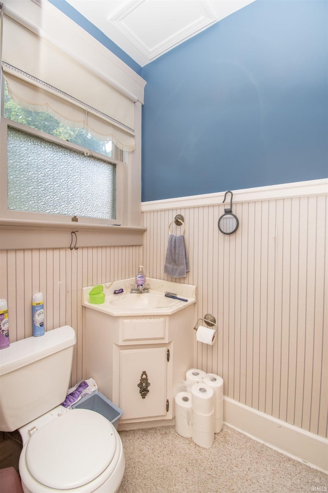 half bath featuring toilet, vanity, and wainscoting