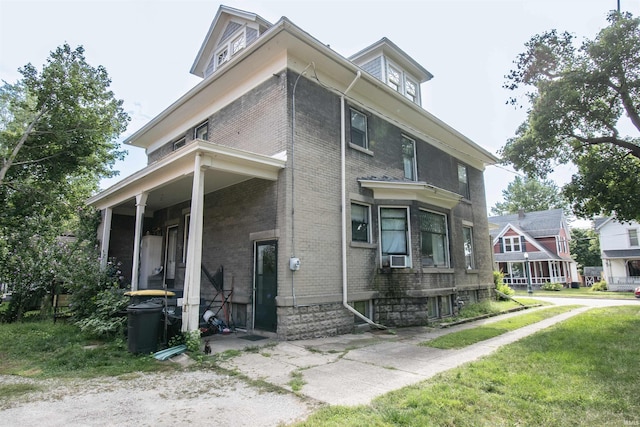 american foursquare style home with covered porch, brick siding, and a front lawn