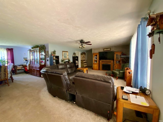 living room with ceiling fan, a textured ceiling, and light carpet