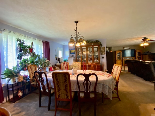 dining area with carpet and ceiling fan with notable chandelier