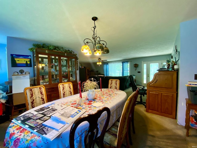 carpeted dining space featuring ceiling fan with notable chandelier and a textured ceiling