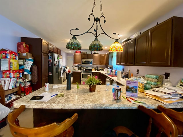 kitchen with hanging light fixtures, appliances with stainless steel finishes, light stone counters, sink, and kitchen peninsula