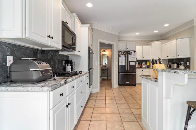 kitchen with light tile patterned flooring, decorative backsplash, black appliances, and white cabinetry