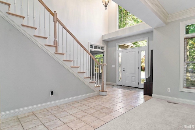 tiled foyer with a high ceiling and crown molding