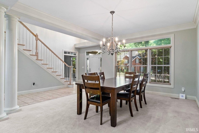 carpeted dining space with ornate columns, a notable chandelier, and ornamental molding