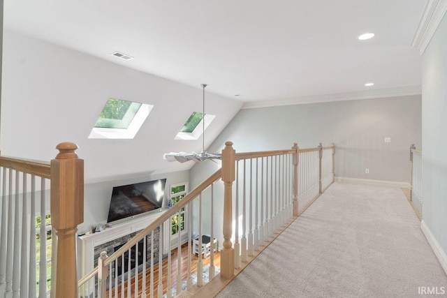 corridor featuring vaulted ceiling with skylight, crown molding, and carpet flooring