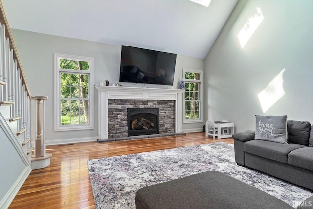 living room with hardwood / wood-style flooring, high vaulted ceiling, and a fireplace