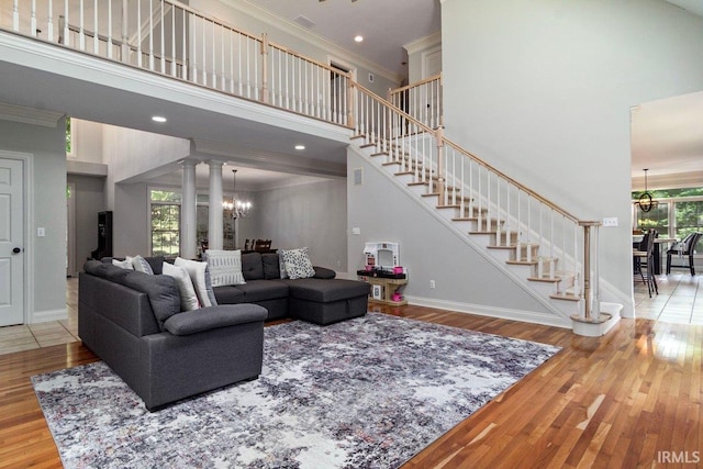 living room featuring a towering ceiling, light hardwood / wood-style flooring, decorative columns, and a healthy amount of sunlight