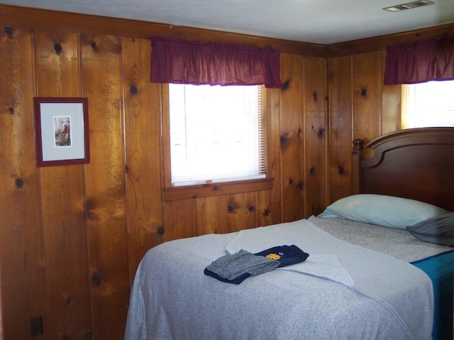 bedroom featuring visible vents and wooden walls