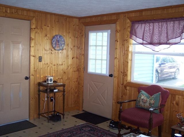 doorway to outside with a healthy amount of sunlight, wood walls, ornamental molding, and tile patterned floors