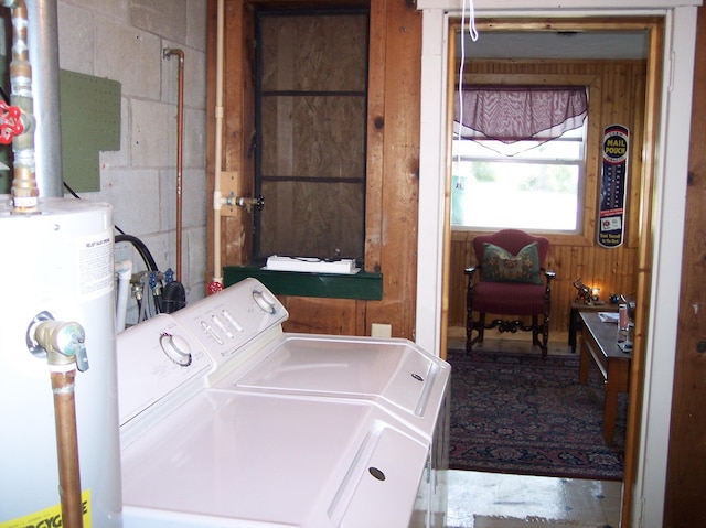 clothes washing area featuring laundry area, gas water heater, washing machine and clothes dryer, and wooden walls