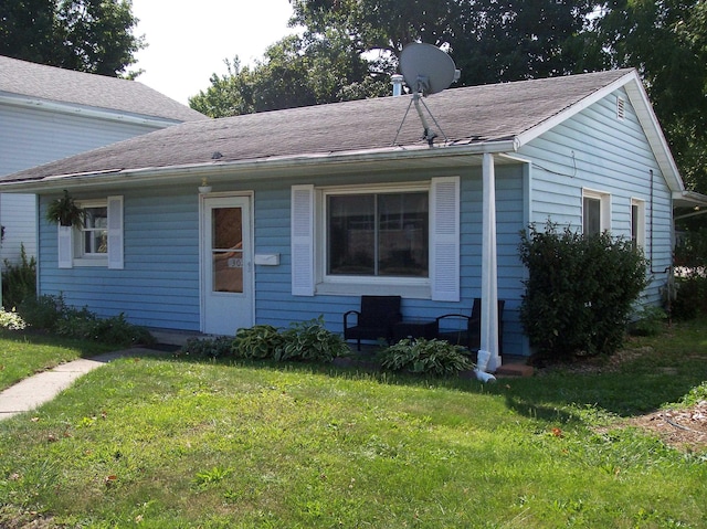 view of front of home with a shingled roof and a front lawn