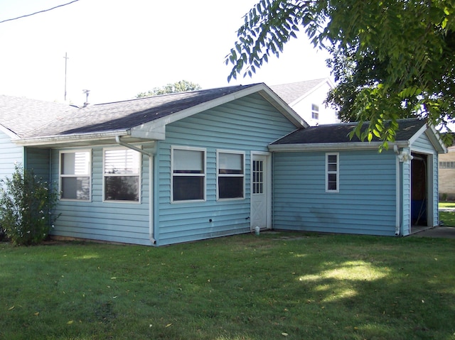 back of property featuring roof with shingles and a lawn