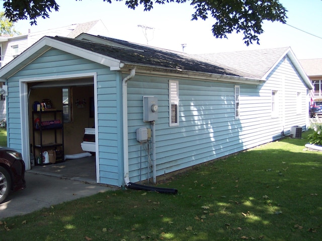 view of side of property featuring a garage, cooling unit, a lawn, and roof with shingles