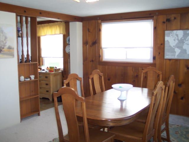 dining space with light carpet and wood walls