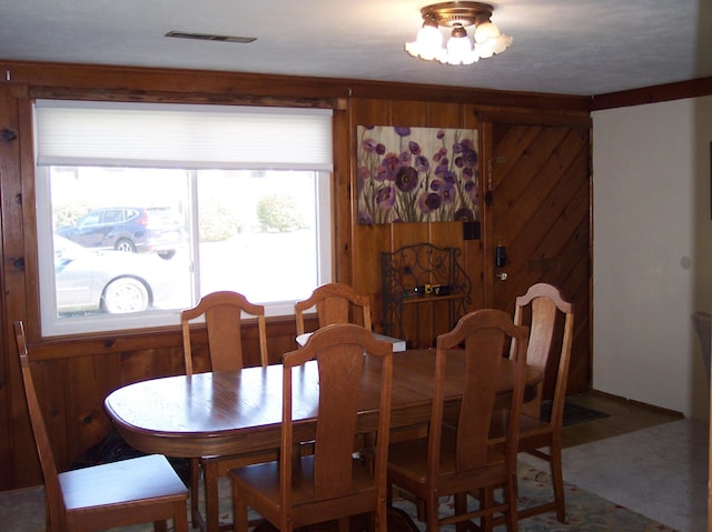 dining space featuring visible vents and wooden walls