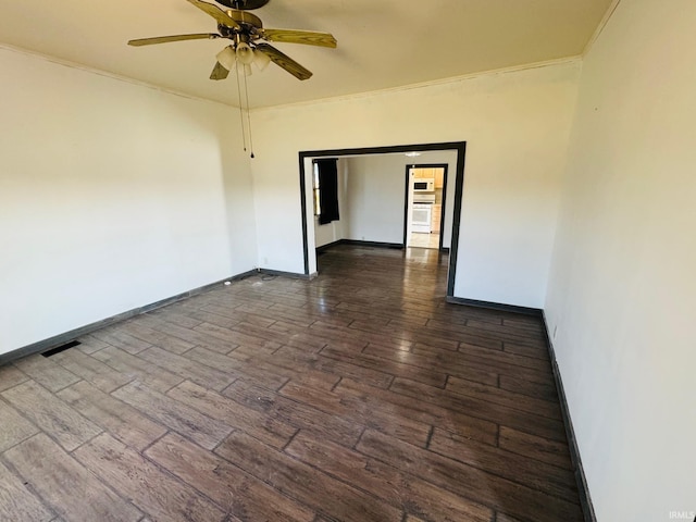 spare room featuring ceiling fan, dark wood-type flooring, visible vents, baseboards, and ornamental molding