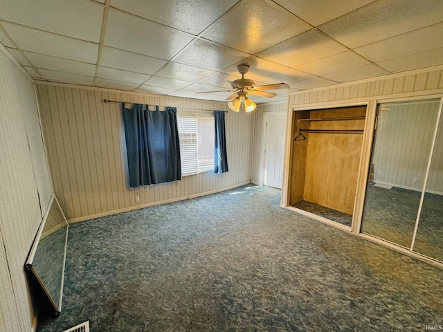 unfurnished bedroom featuring baseboards, a ceiling fan, carpet, a paneled ceiling, and a closet