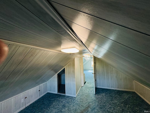 additional living space with carpet floors, lofted ceiling, and wooden walls