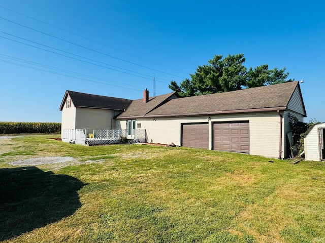 rear view of property with a yard and a garage