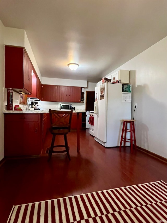 kitchen featuring kitchen peninsula, dark hardwood / wood-style flooring, a kitchen breakfast bar, and white refrigerator