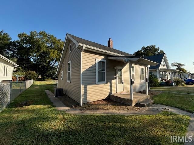 view of front of house with central AC unit and a front lawn