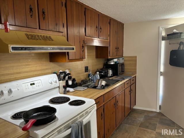 kitchen with dark tile patterned floors, white range with electric cooktop, a textured ceiling, and custom exhaust hood