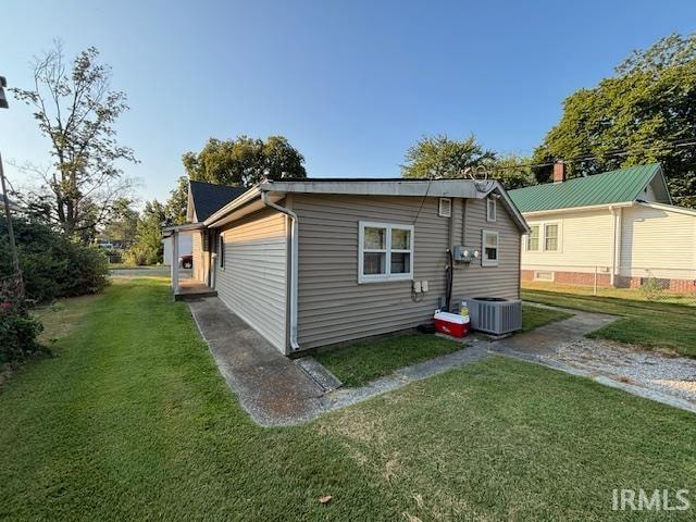 rear view of property featuring a lawn and central AC