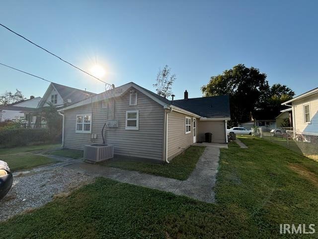 view of property exterior with central AC and a yard