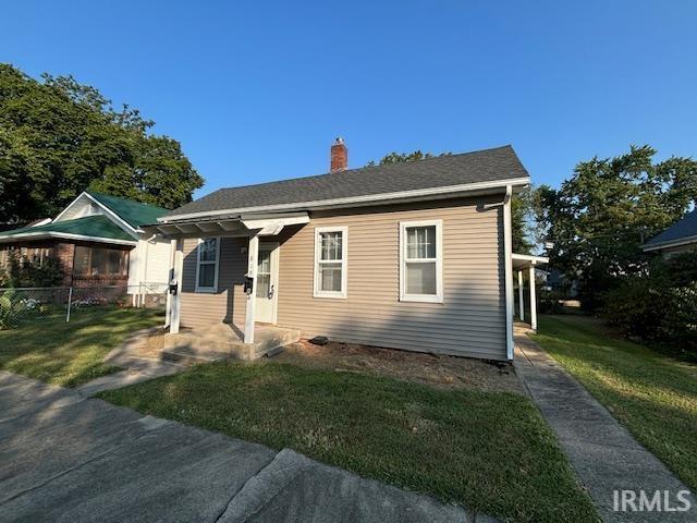 bungalow-style house featuring a chimney, fence, and a front lawn