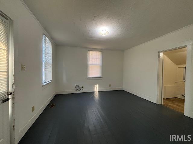 empty room with dark hardwood / wood-style floors and ornamental molding