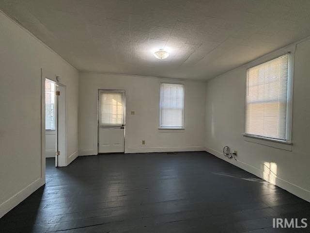 spare room featuring dark wood-style floors and baseboards