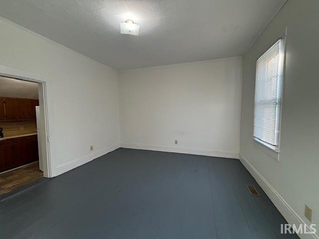 unfurnished room featuring dark wood-style flooring, visible vents, and baseboards